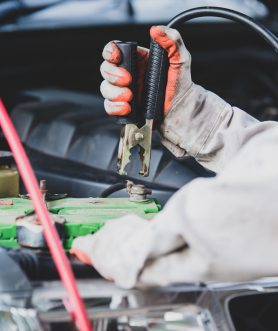 Car repairman wearing a white uniform standing and holding a wre Car repairman wearing a white uniform standing and holding a wrench that is an essential tool for a mechanic